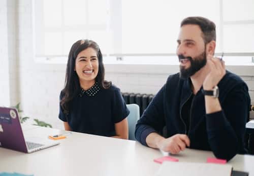 A man and a woman smiling in a business meeting